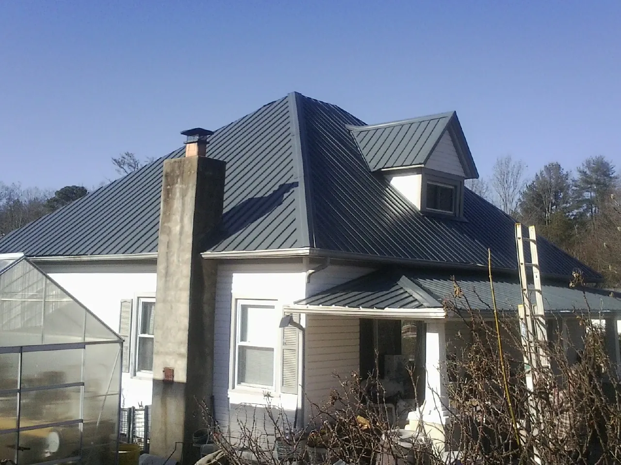 Dark blue standing seam metal roof on a white farmhouse with dormer — Slate & Tile Roof Repair by Roofing Brothers in New Bremen