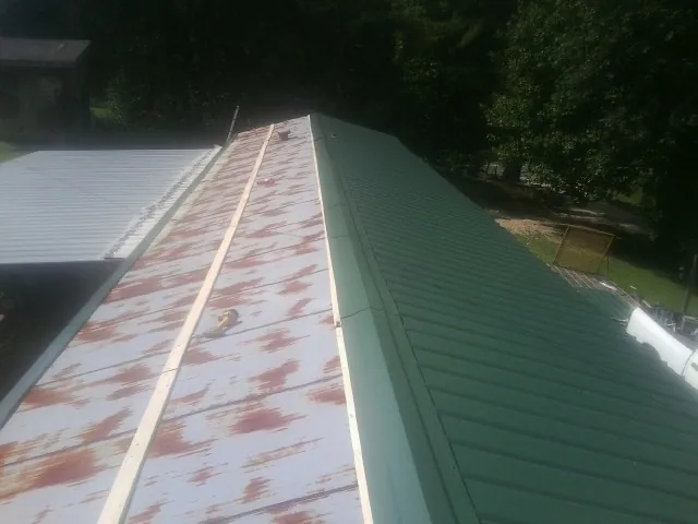 Old rusted panels beside newly installed green metal roofing — Wind Damage Roof Repair by Roofing Brothers in New Bremen