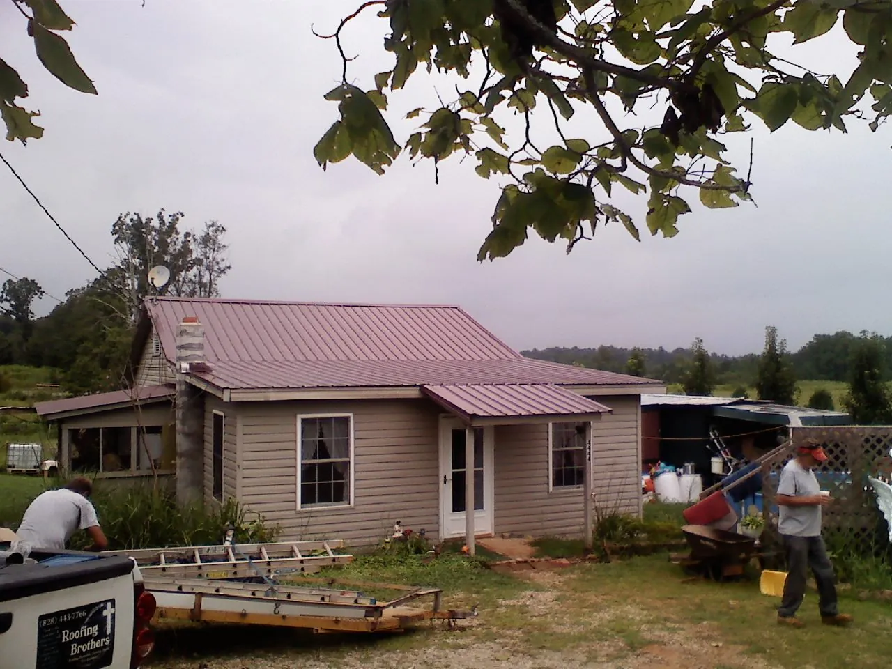 Crew finishing a mauve metal roof on a small farmhouse in New Bremen