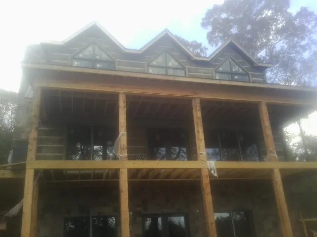 Dormers and porch framing on a large log home under construction — Roof Coating work by our crew in New Bremen