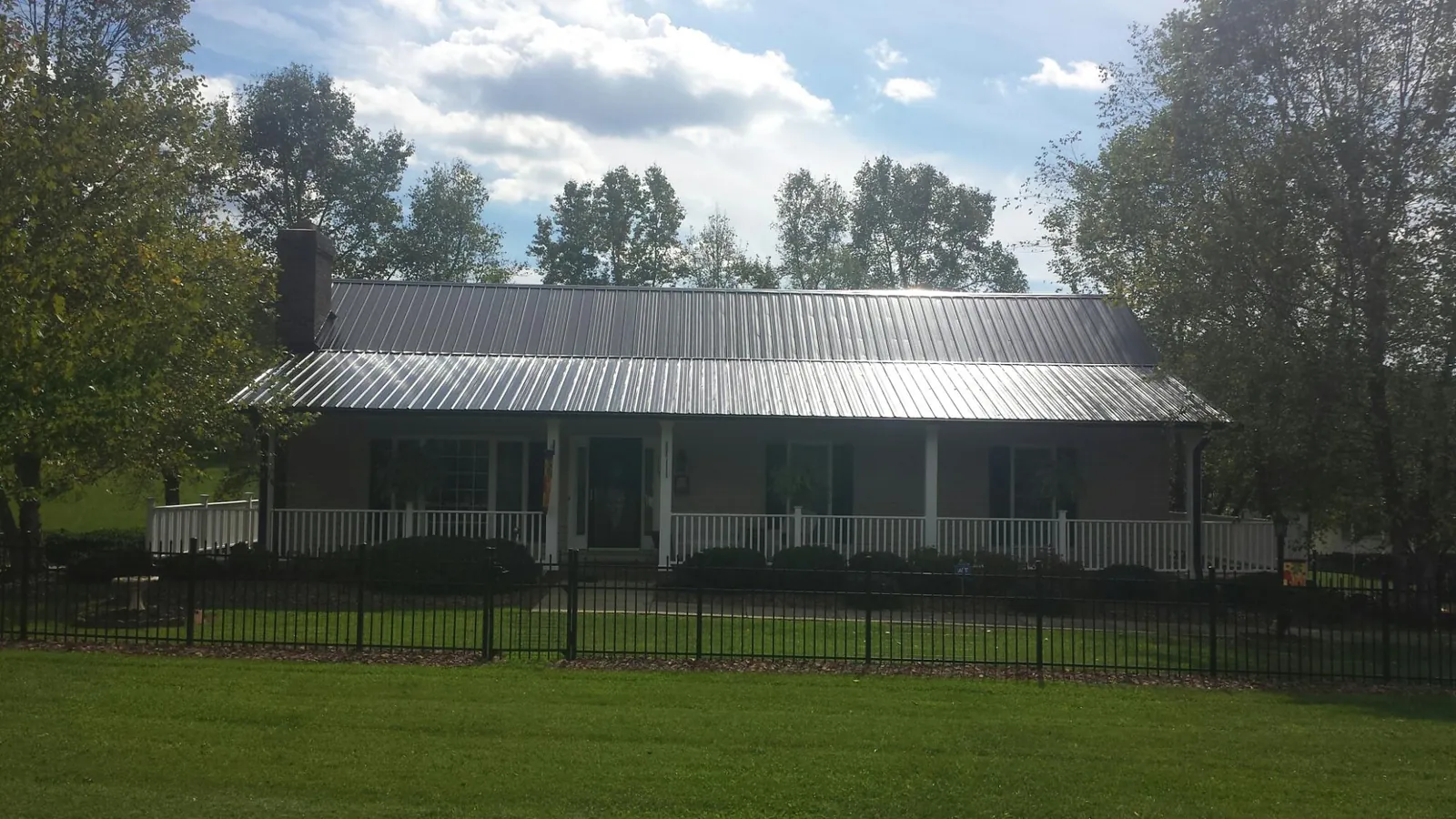 Gray metal roof on a brick ranch with a full width front porch — Gutter Guard Installation work by our crew in New Bremen