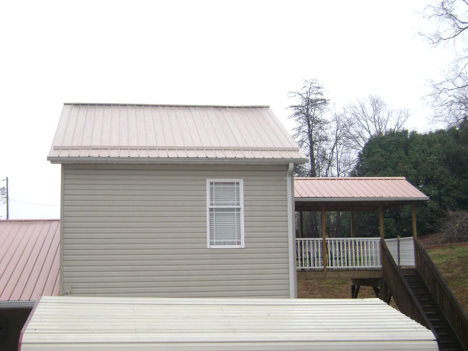 Tan metal roofs on a two story addition and attached porch, from a Roof Replacement job in New Bremen